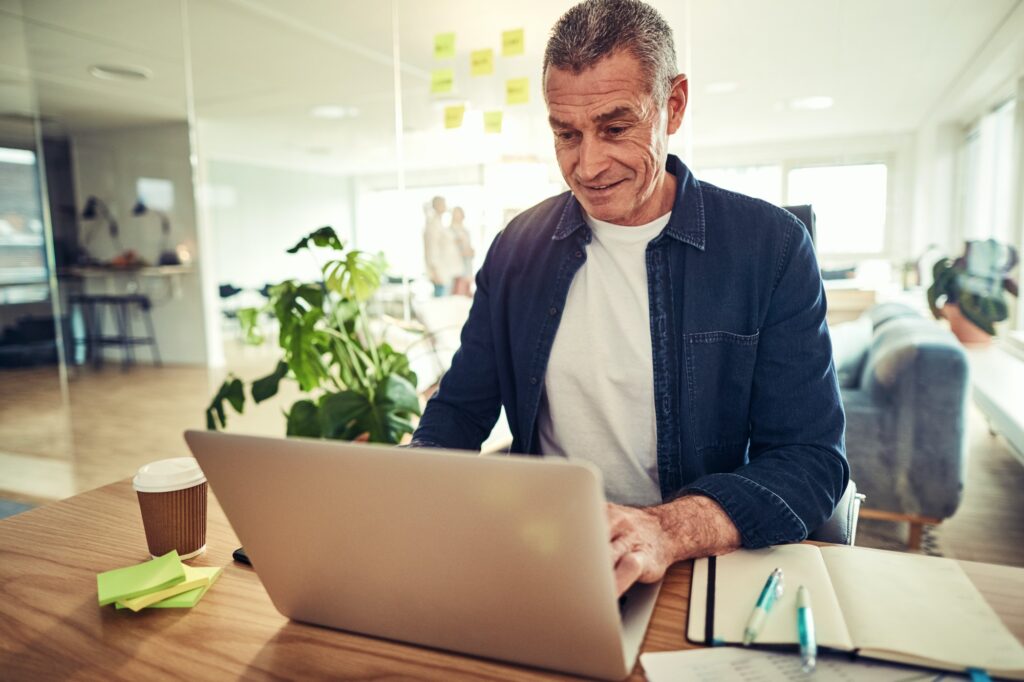 Smiling mature businessman working on a laptop in an office